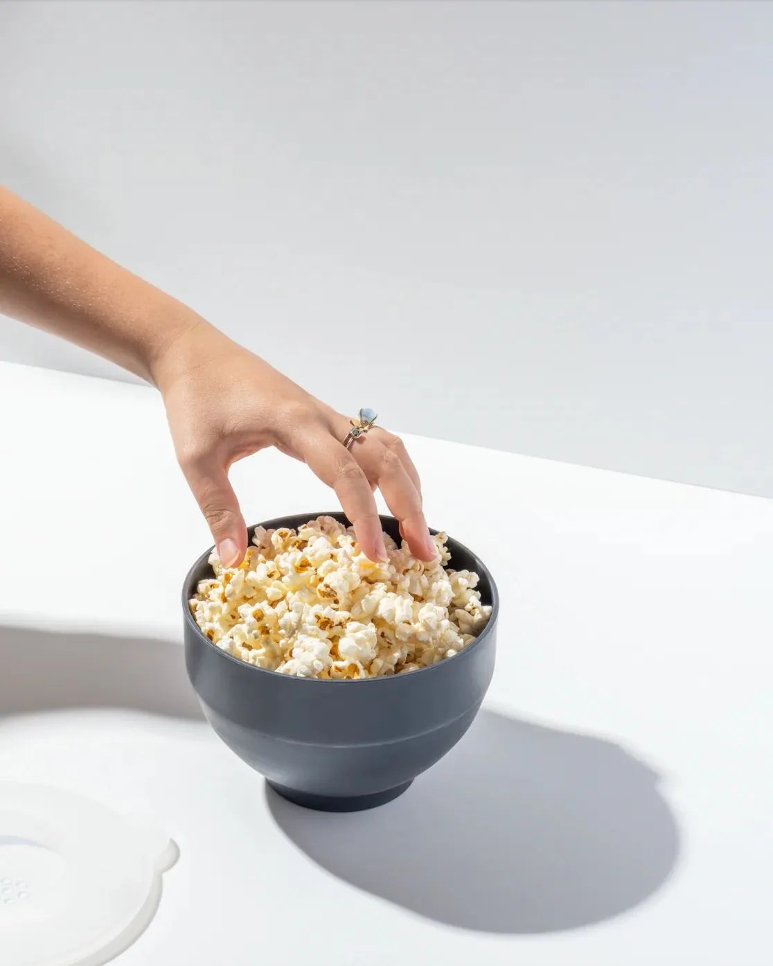 a hand reaching into a bowl of popcorn