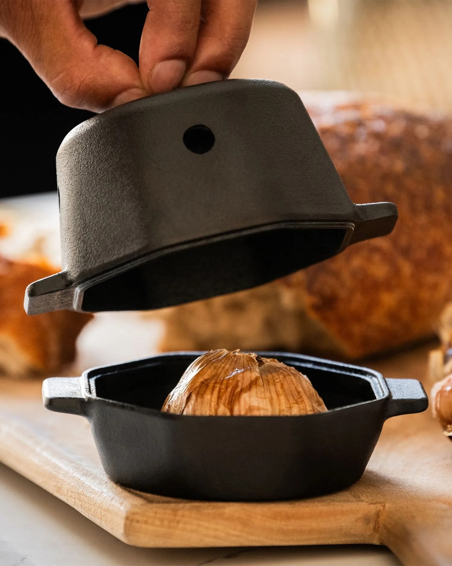 a hand holding a black hat over a wooden surface