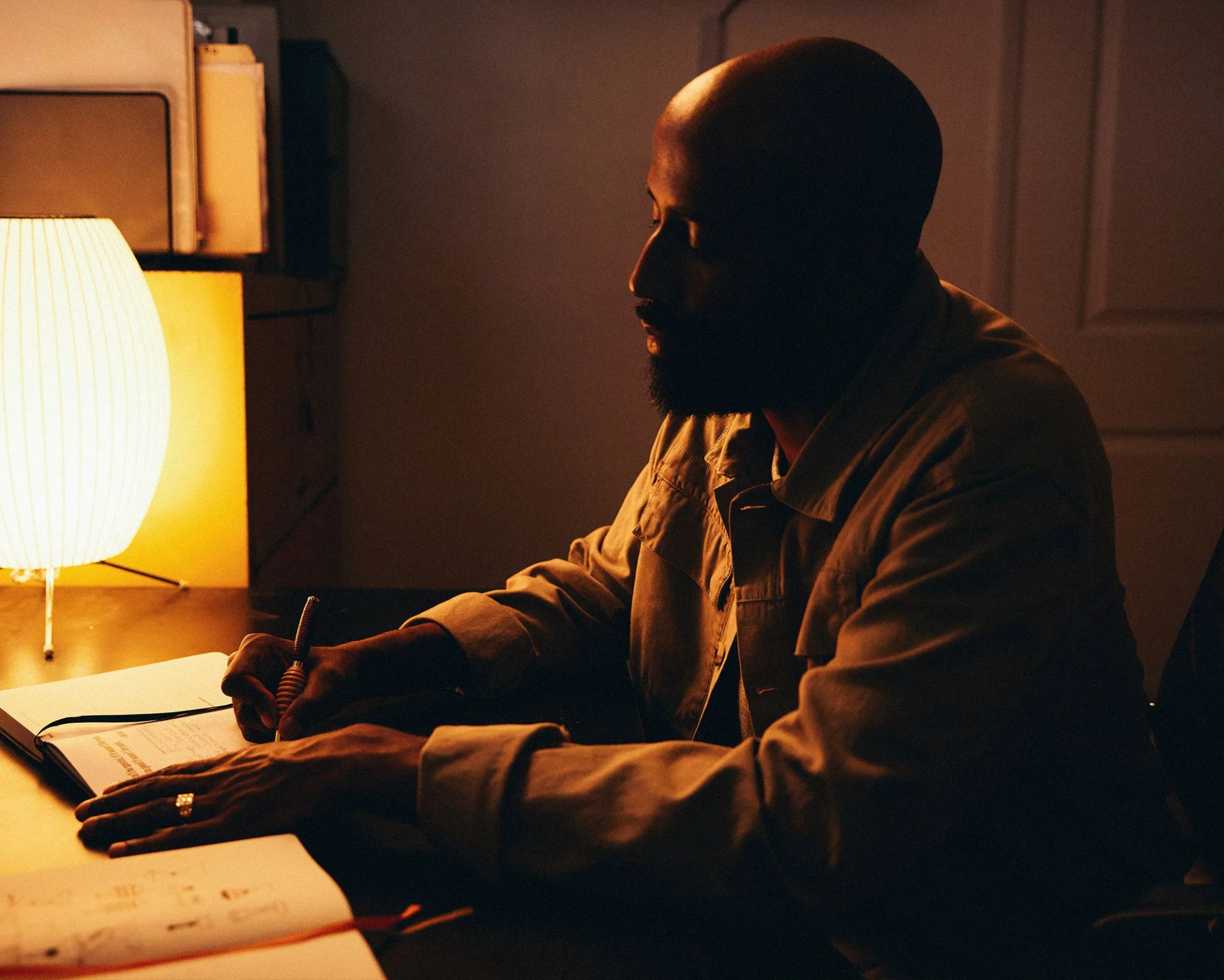 Cedric Mitchell writing in notebook at desk