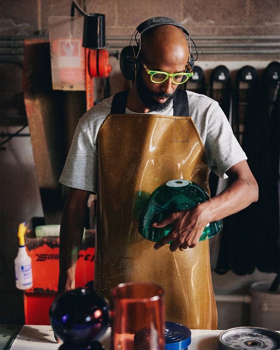 Cedric Mitchell examining his blown glass bowl in studio