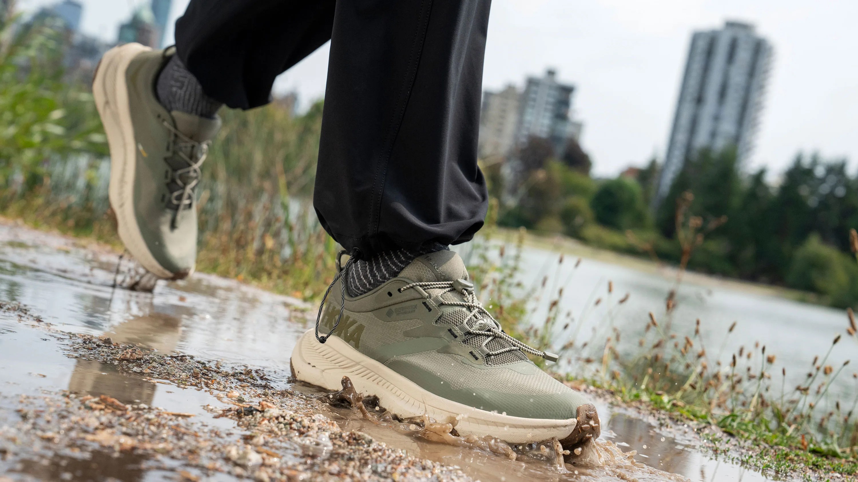 person wearing hoka sneaker stepping through puddle