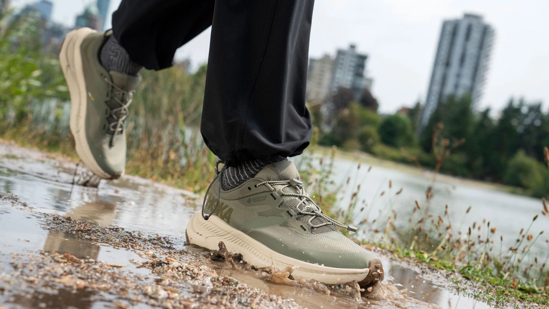person wearing hoka sneaker stepping through puddle