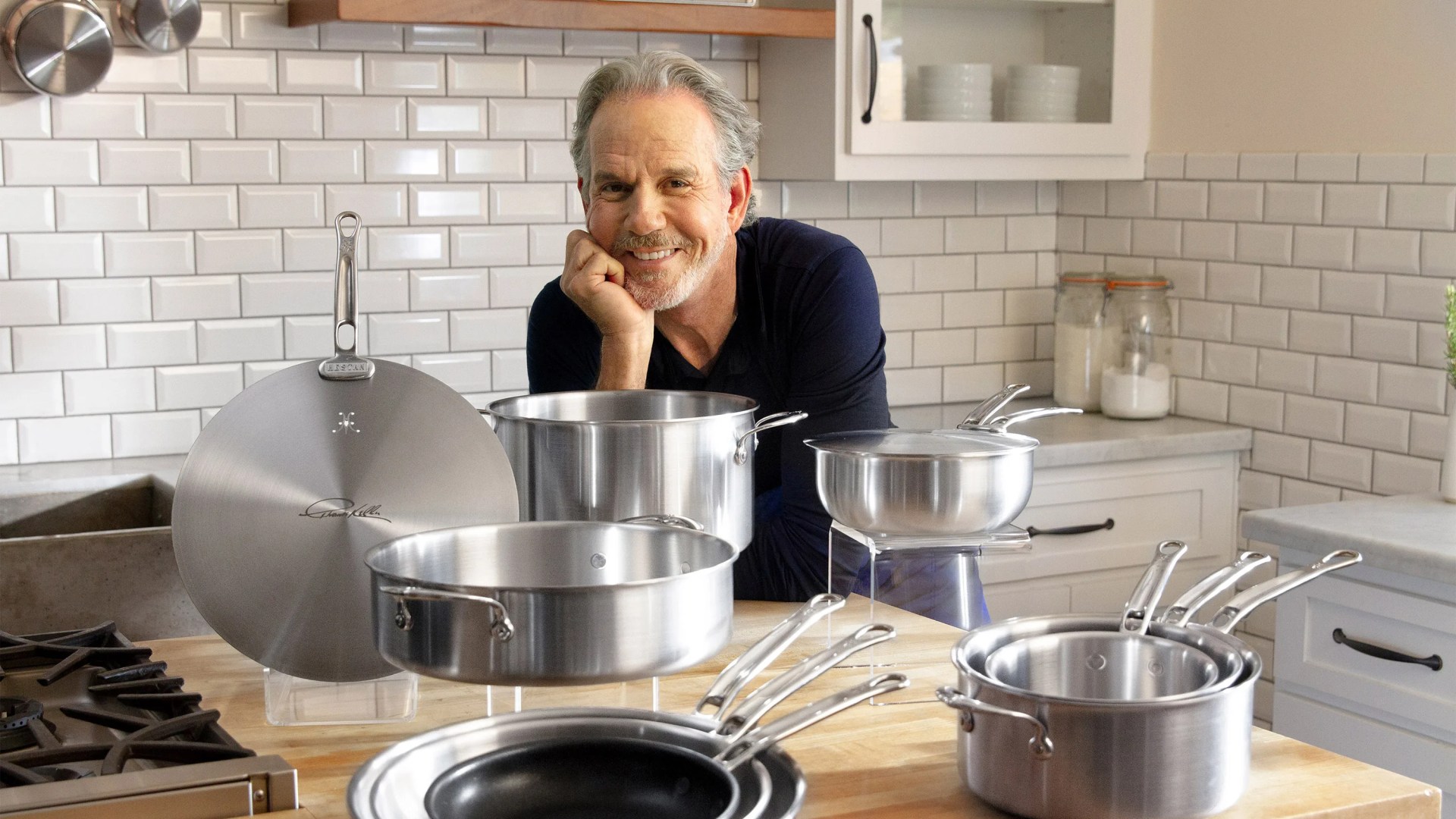 a man leaning on his elbow in front of hestan 11 piece cookware