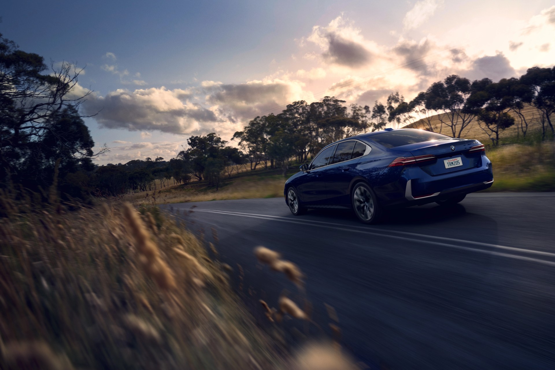 the 2024 bmw 5 series driving away from you on a country road