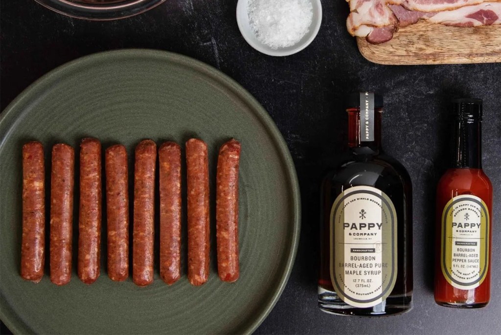a plate of hot dogs and bottles of sauce on a table