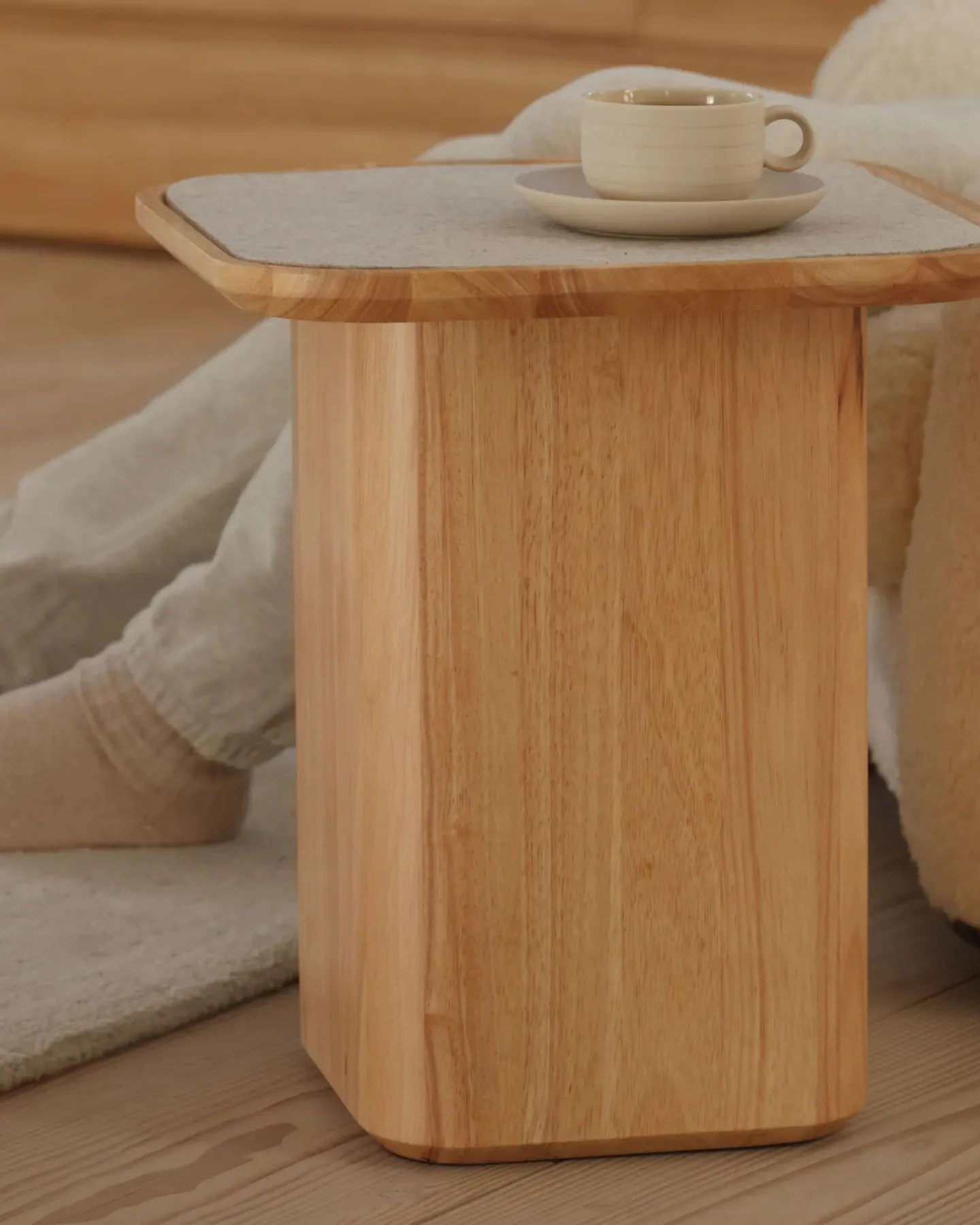 a person sitting on couch using thuma pedestal side table