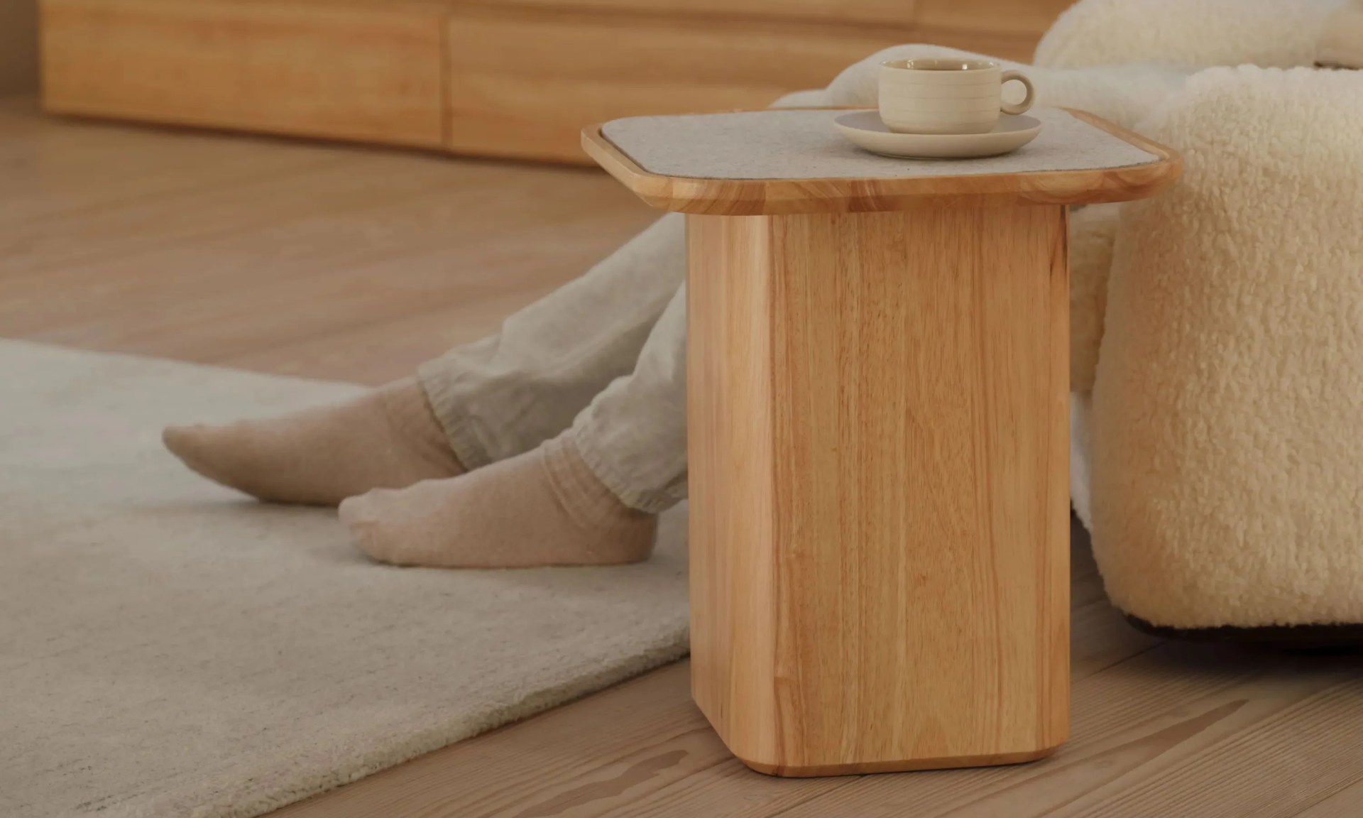 a person sitting on couch using thuma pedestal side table