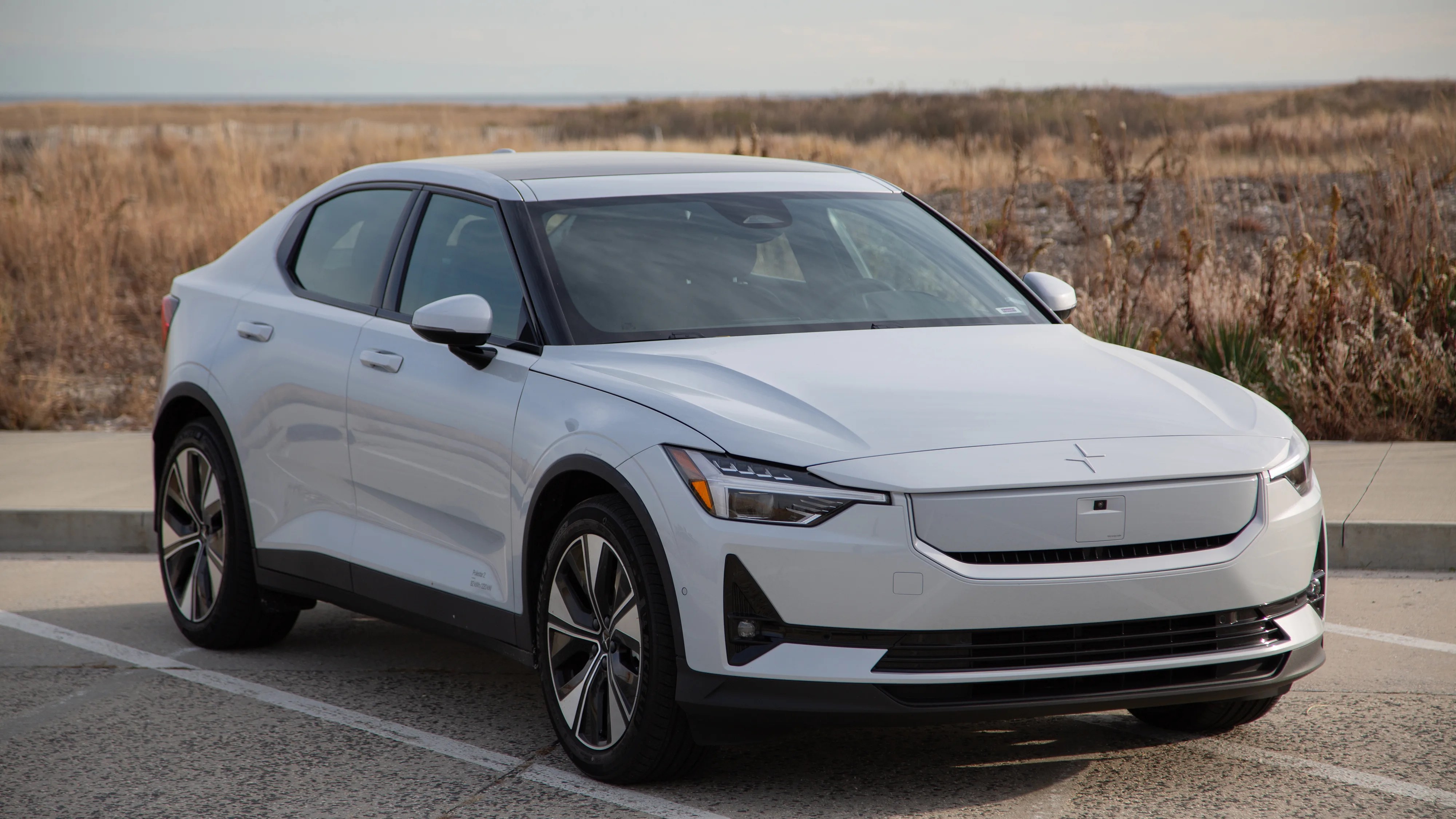 white polestar 2 sedan in front of beach grass in winter
