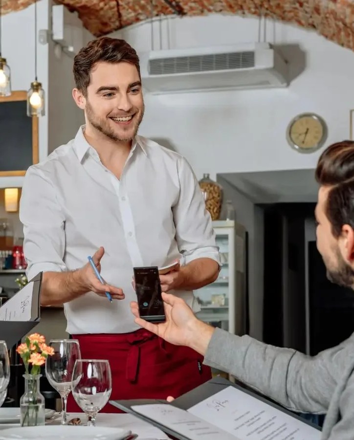 two people using the vasco translator v4 universal translator with 108 languages to talk with the waiter