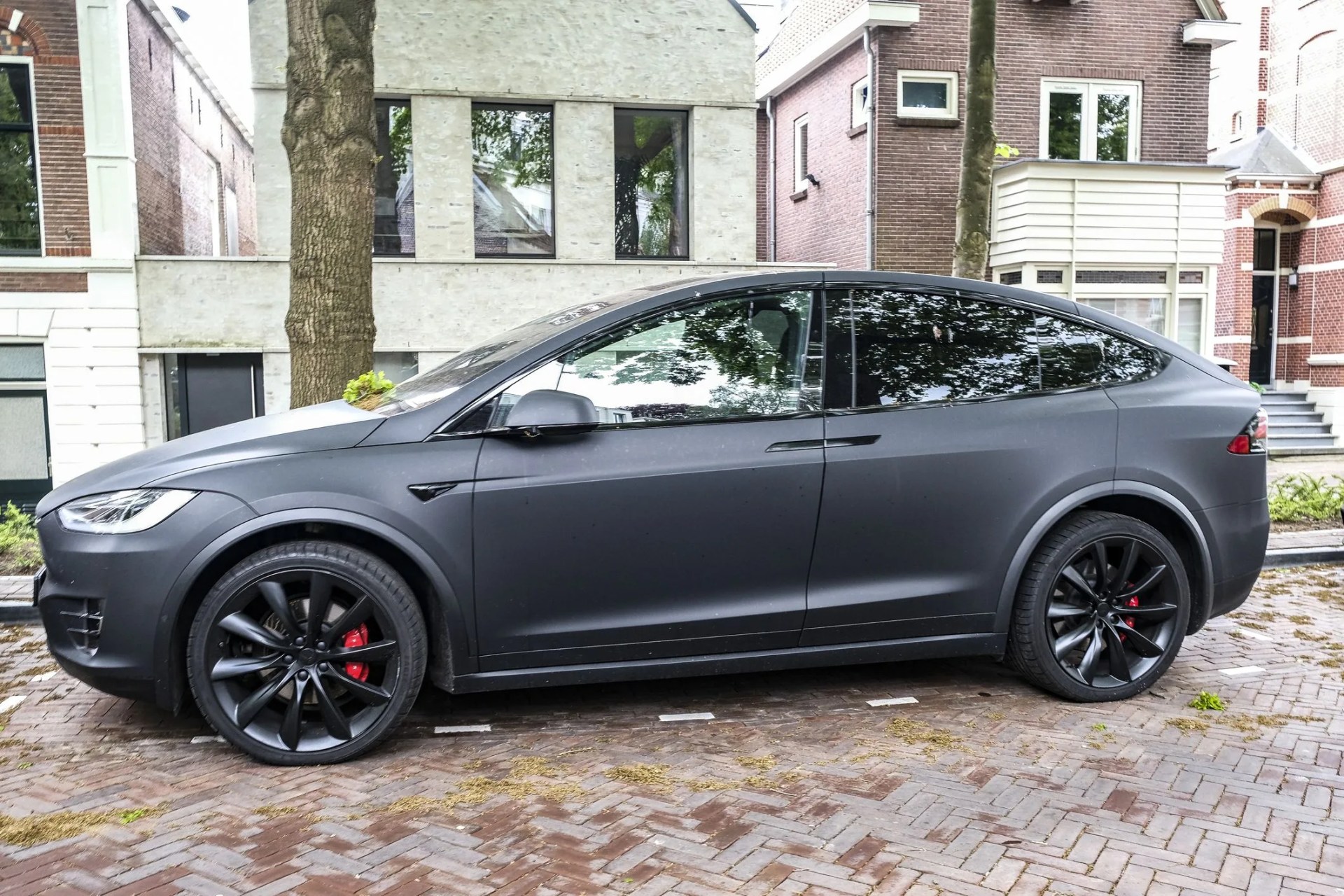 tesla model x electric suv in matte black parked on the street