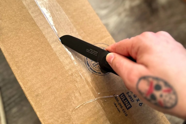 a person opening a box with a knife