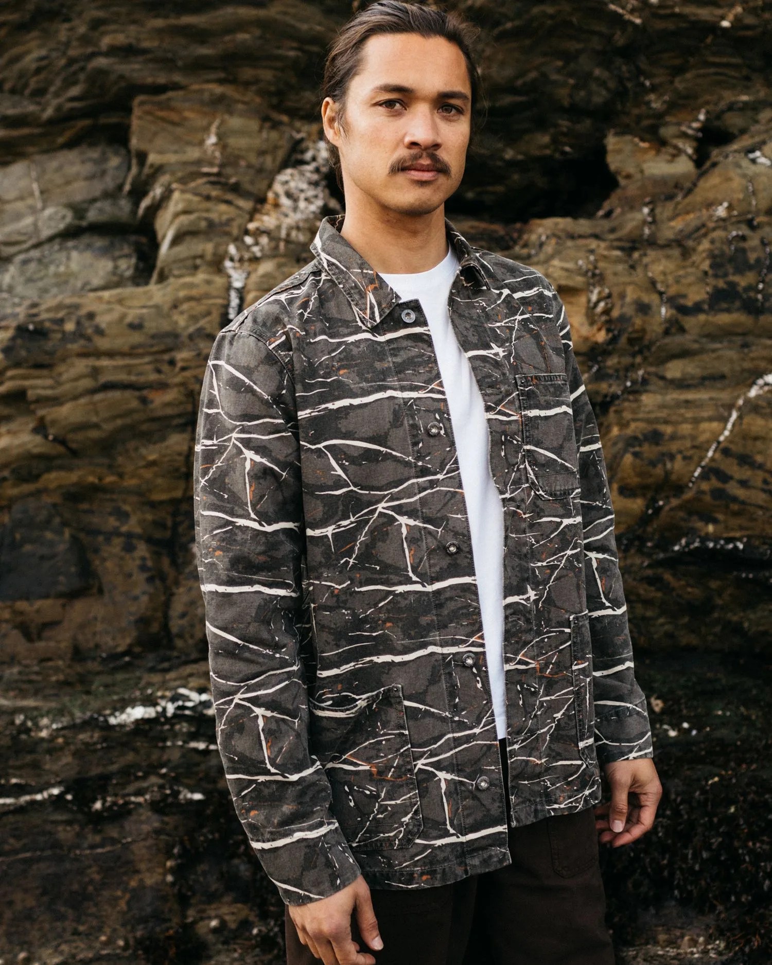 a man standing in front of a rock wall