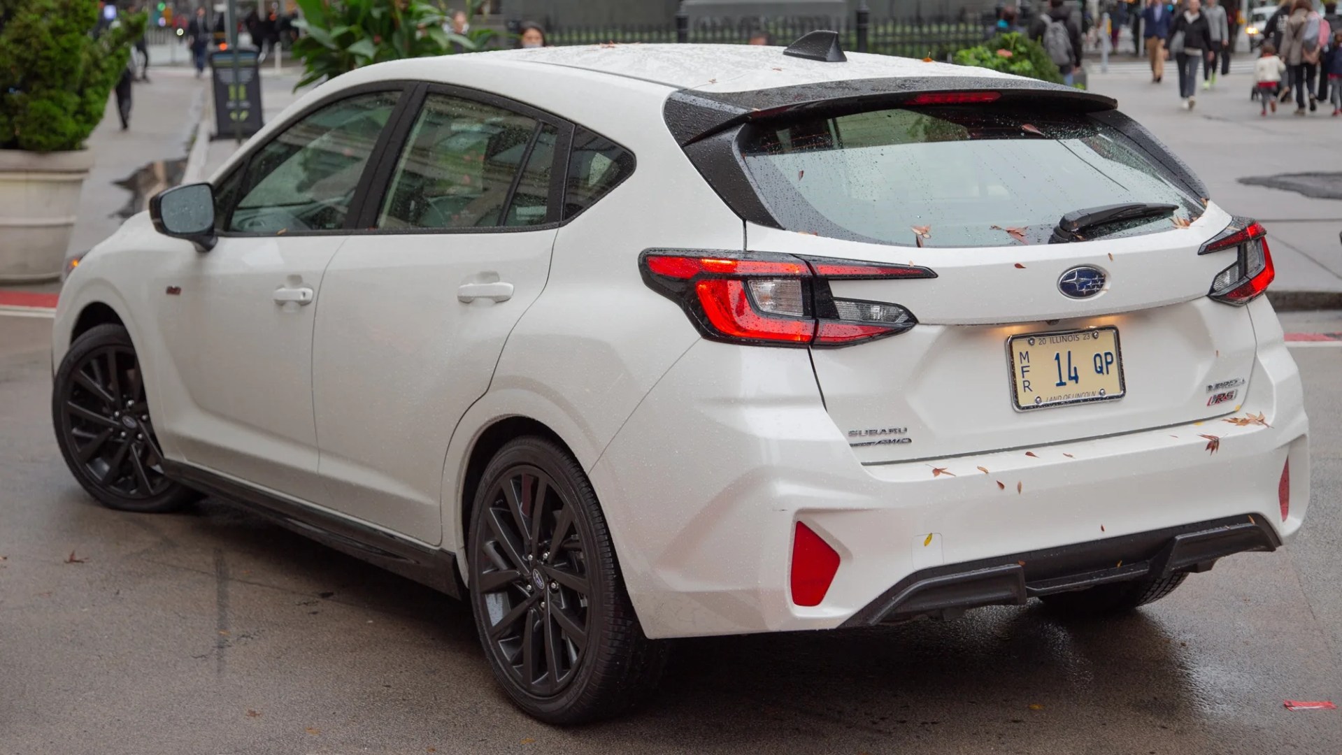 the rear three quarter angle of a white 2024 subaru impreza rs hatchback parked on a city street