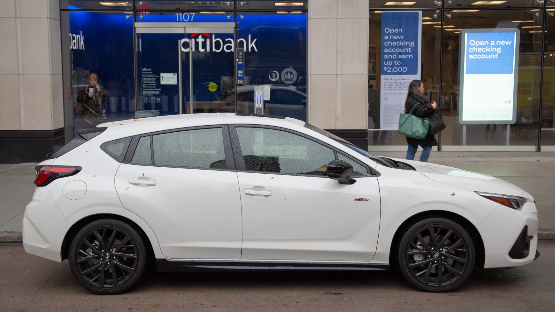side view of a white 2024 subaru impreza rs hatchback parked on a street in front of a bank