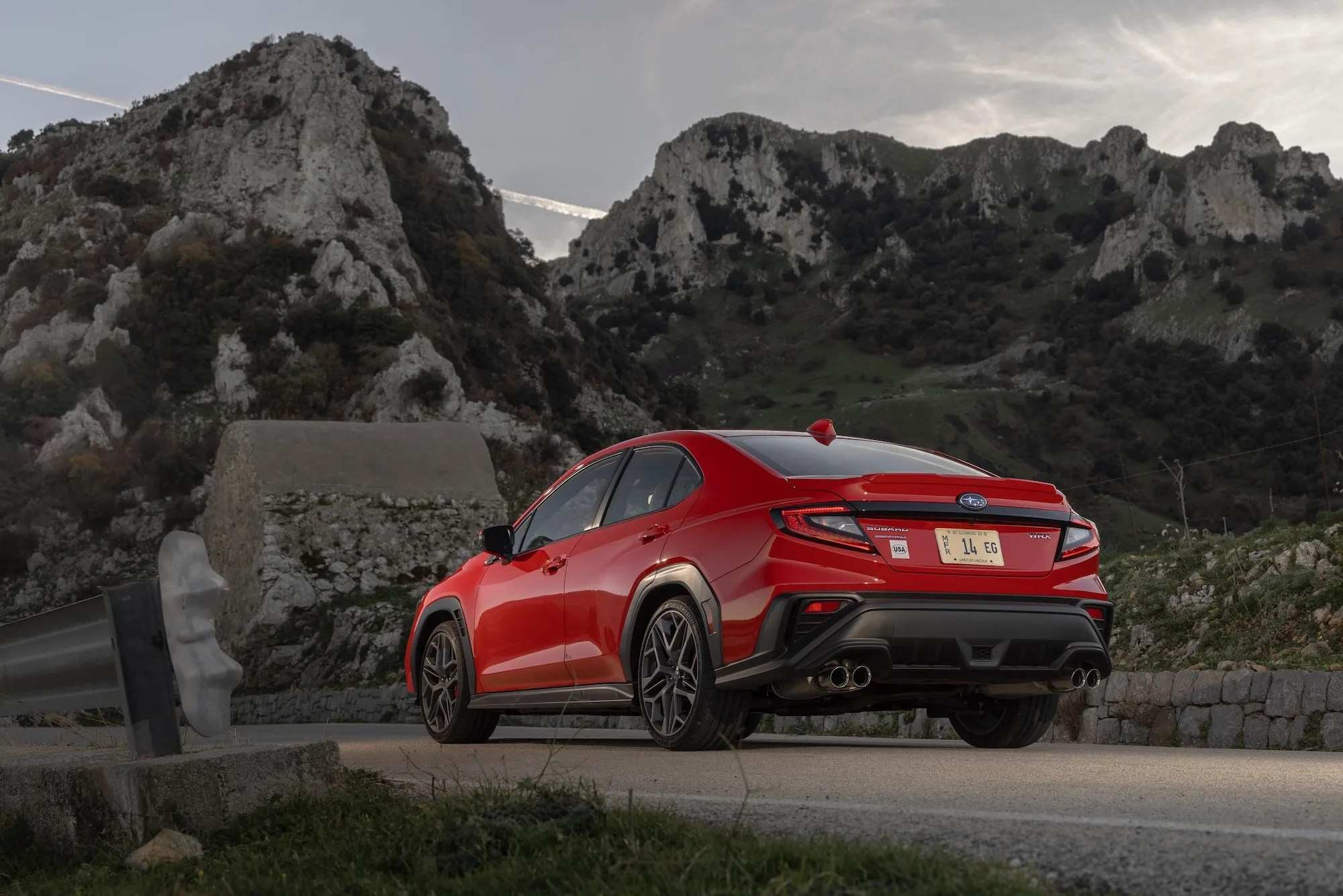 rear three quarter view of a red subaru wrx in front of jagged black volcanic mountains