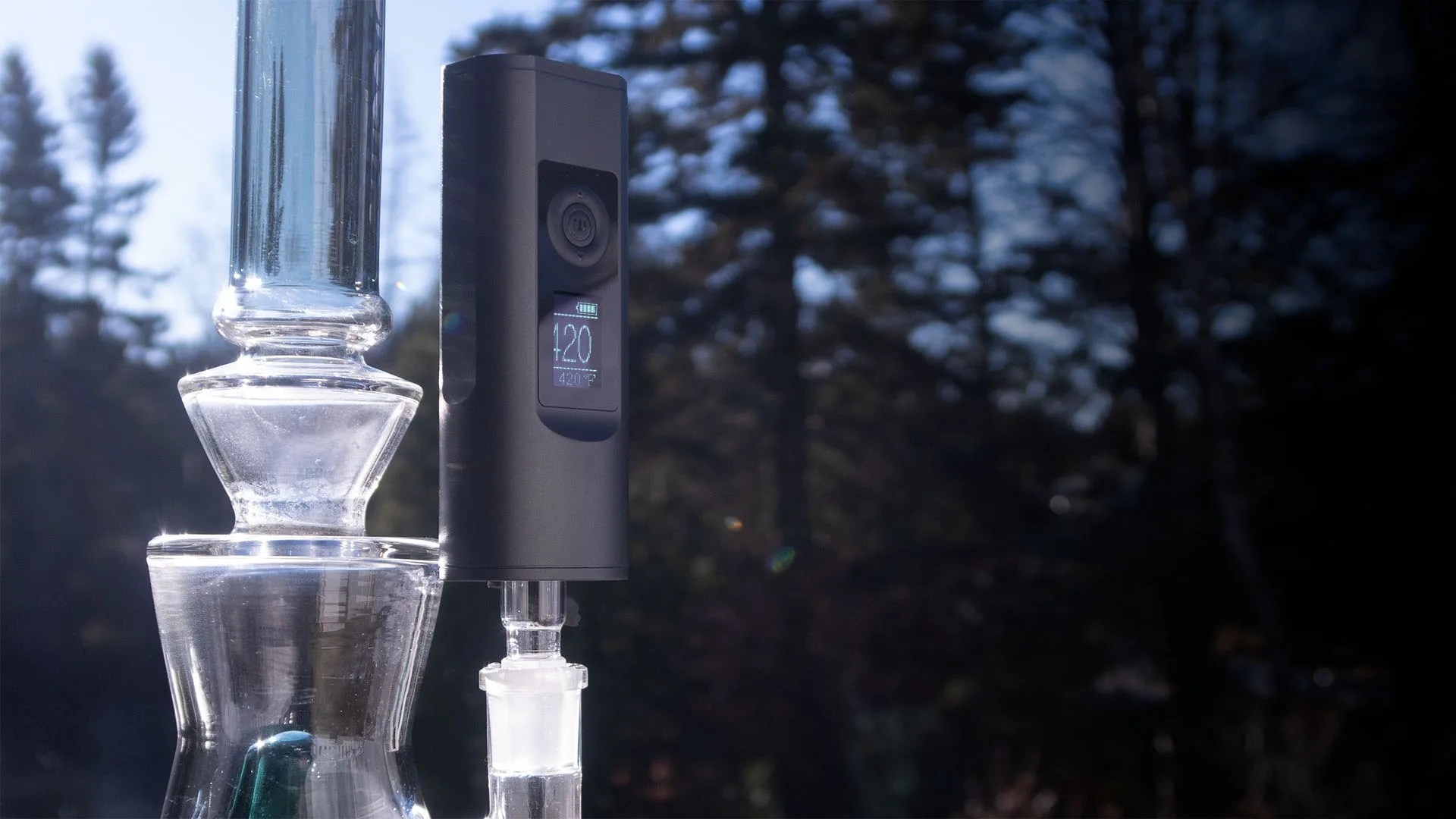 Arizer Solo II MAX with a glass bong in front of trees