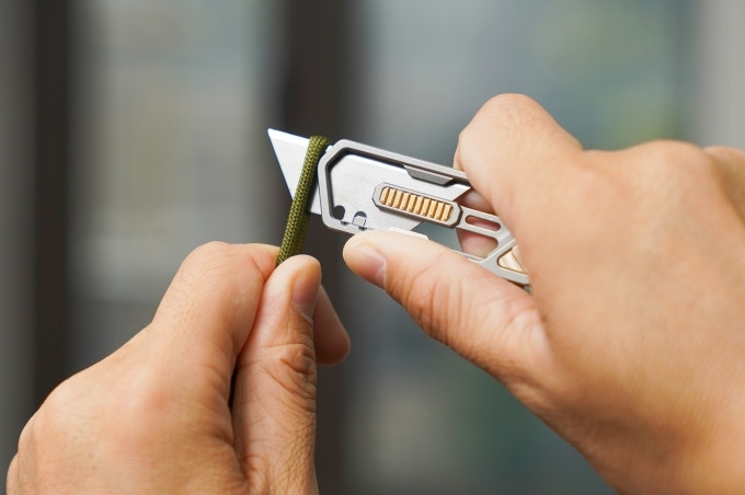 a person cutting paracord with a utility knife