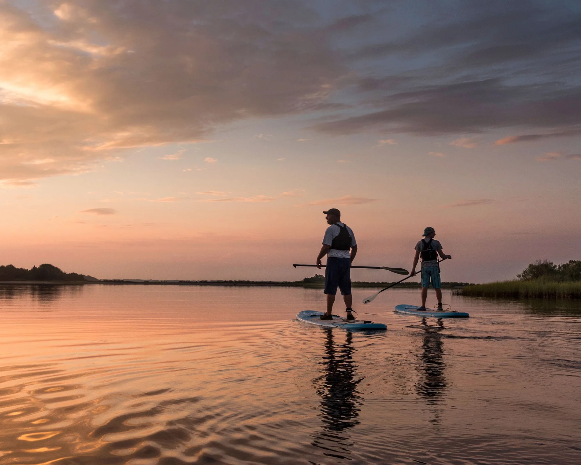 two people paddle boarding at sunset at hammocks beach state park