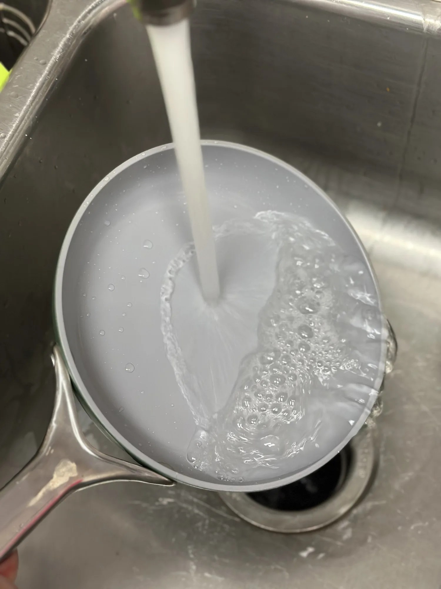 a pan being washed in a sink with a running faucet