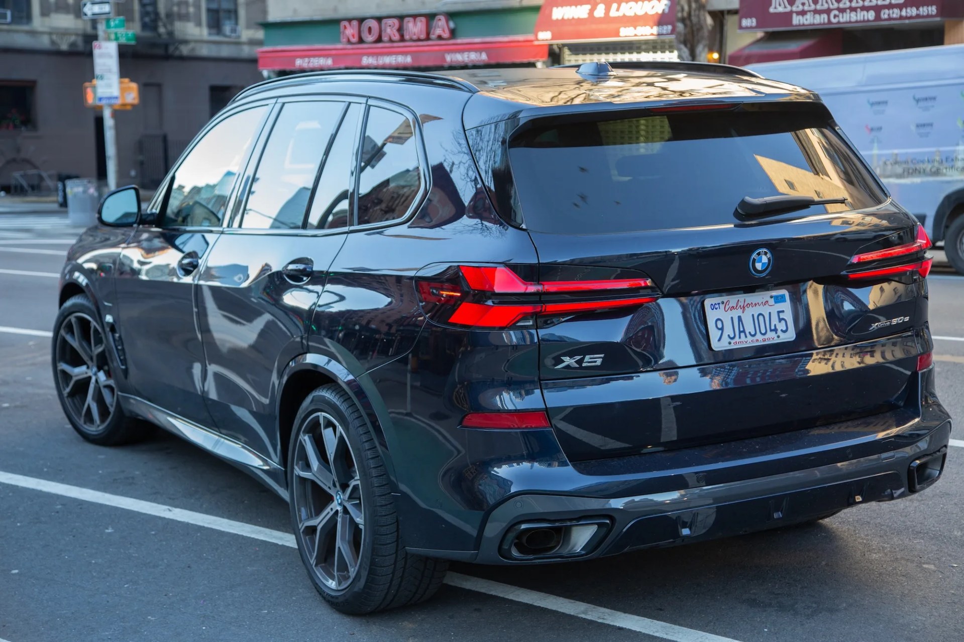 rear three quarter view of a dark blue bmw x5 parked on a city street