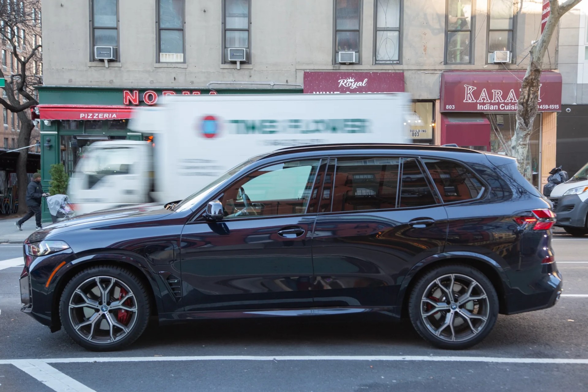 side view of a dark blue bmw x5 parked on a city street