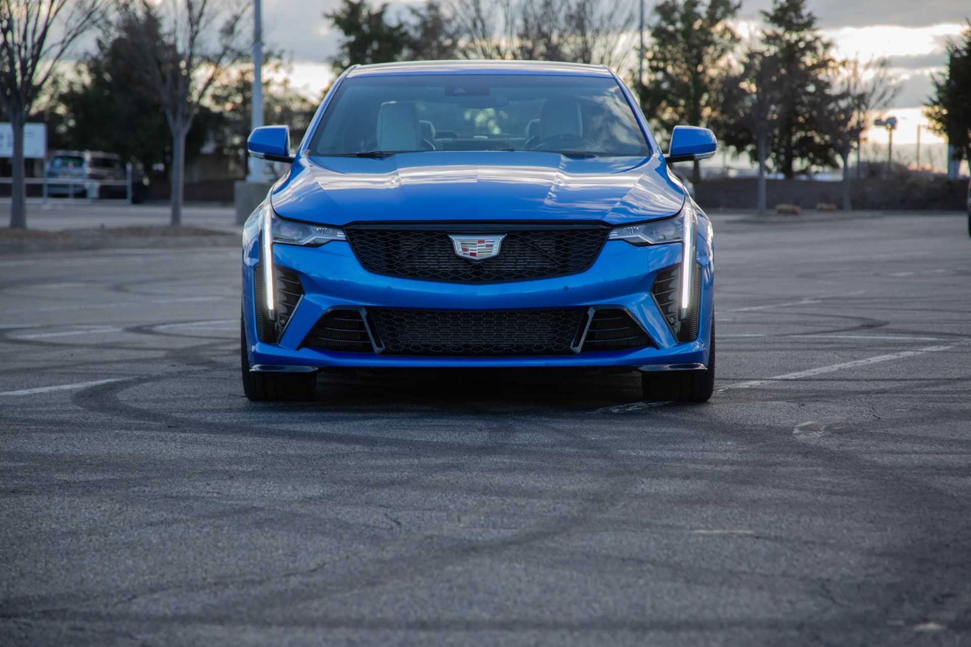 head on view of a blue cadillac ct4 v blackwing in a parking lot over some tire marks