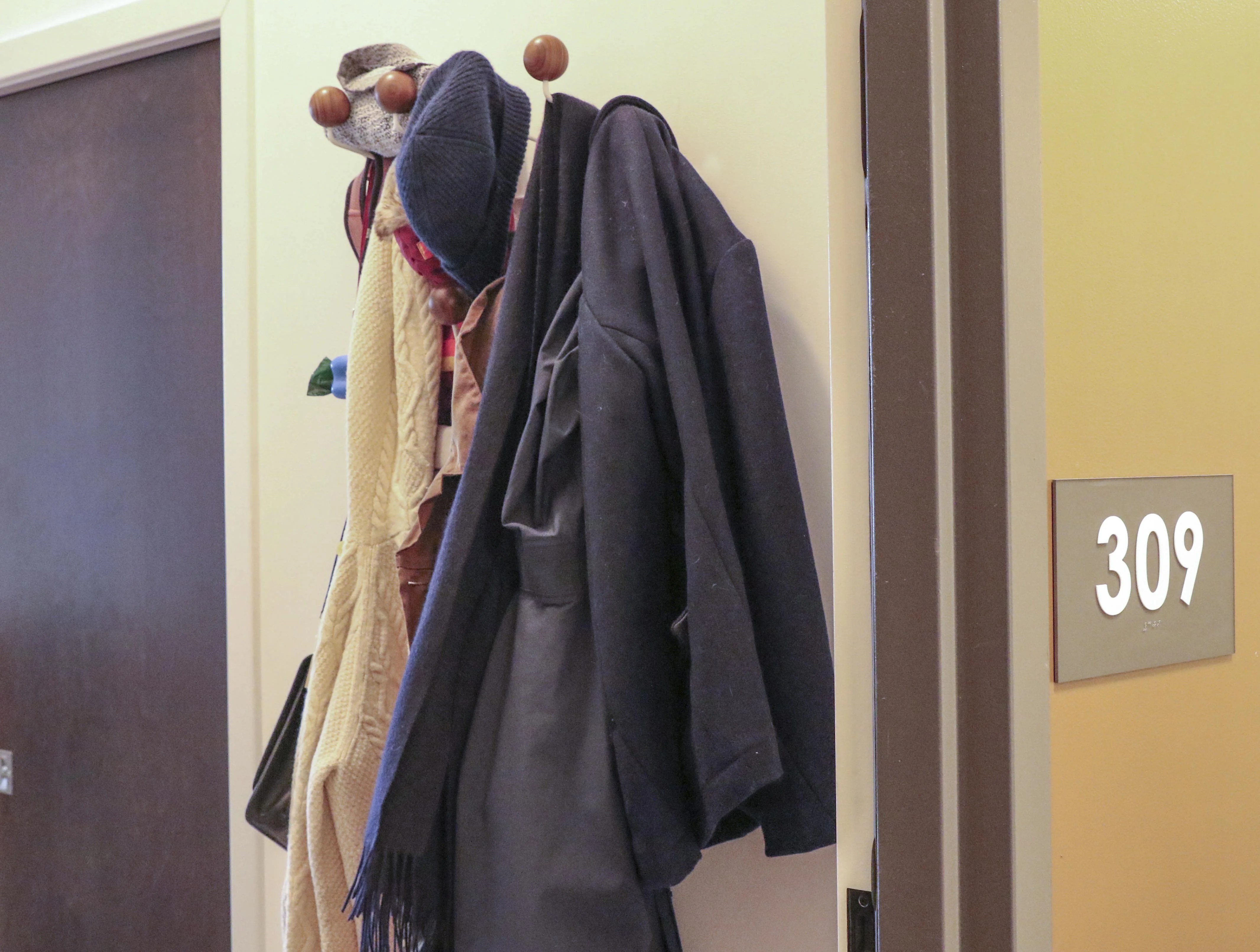 jackets and hats hanging on a coat rack on a door