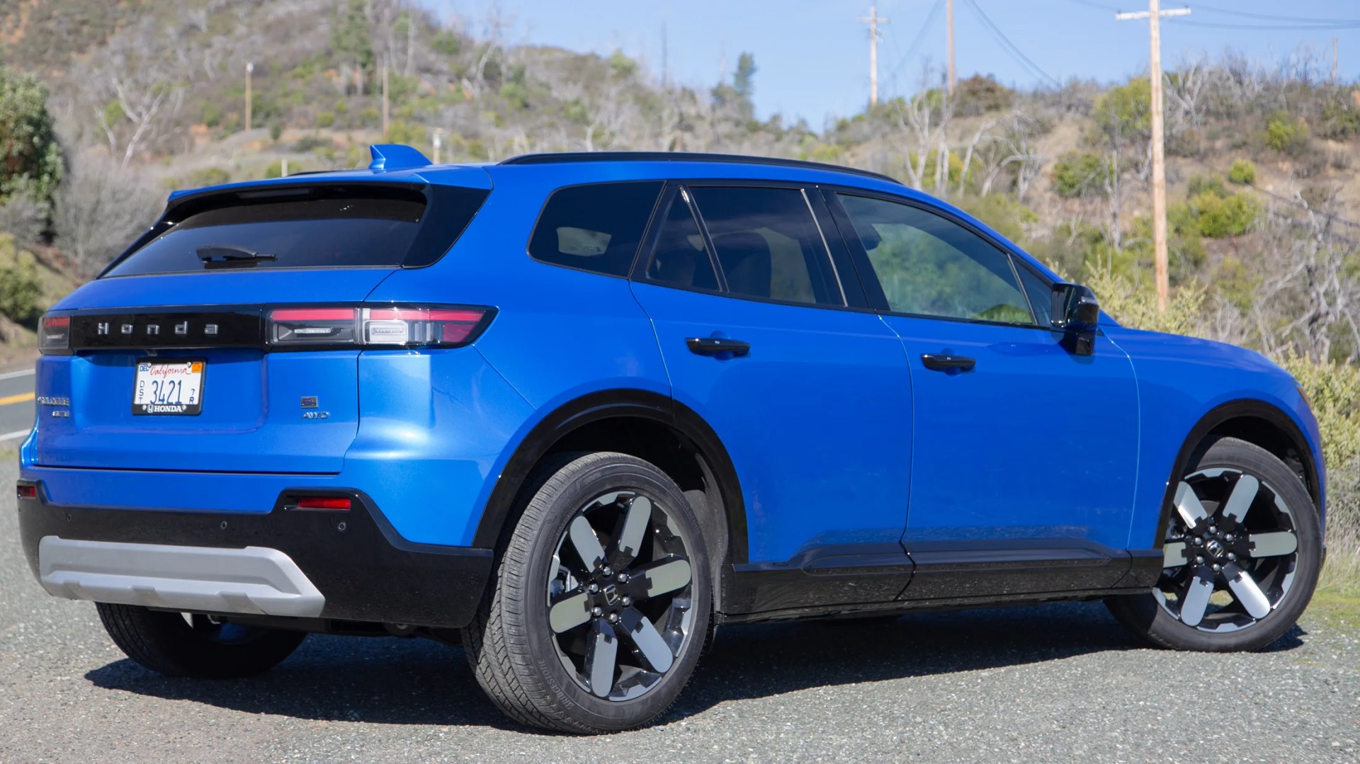 the rear three quarter view of a blue 2024 honda prologue in front of dry hills