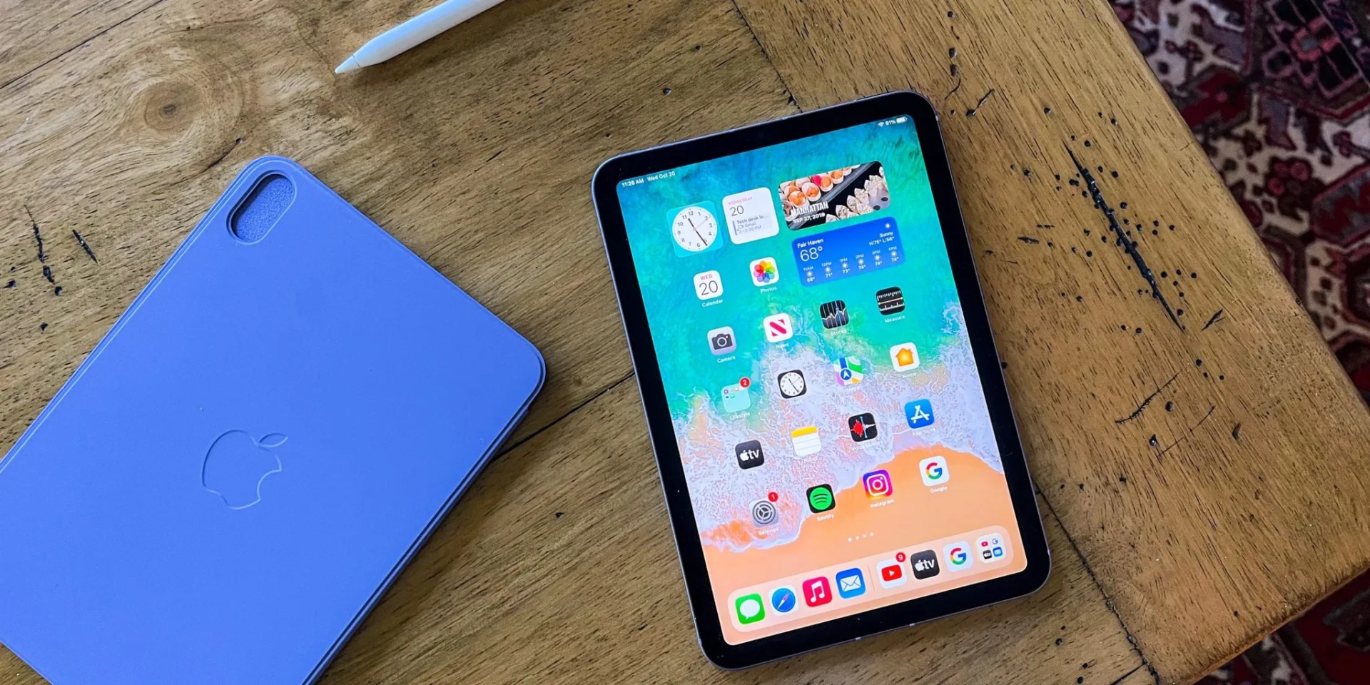 Apple iPad Mini 2021 edition sitting on a wooden table with the screen turned on.
