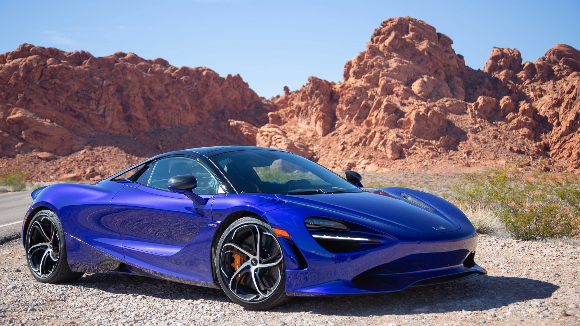 a purple blue mclaren 750s spider parked with red hills in the background