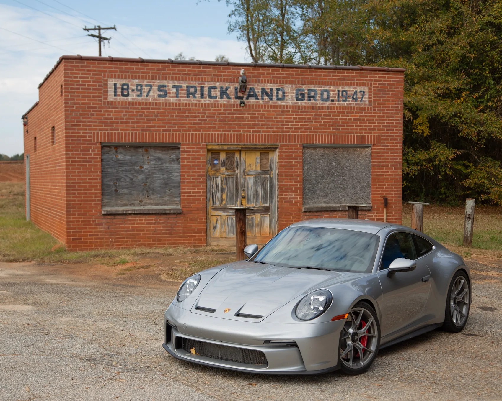 silver porsche 911 gt3 touring in front of a single story brick building
