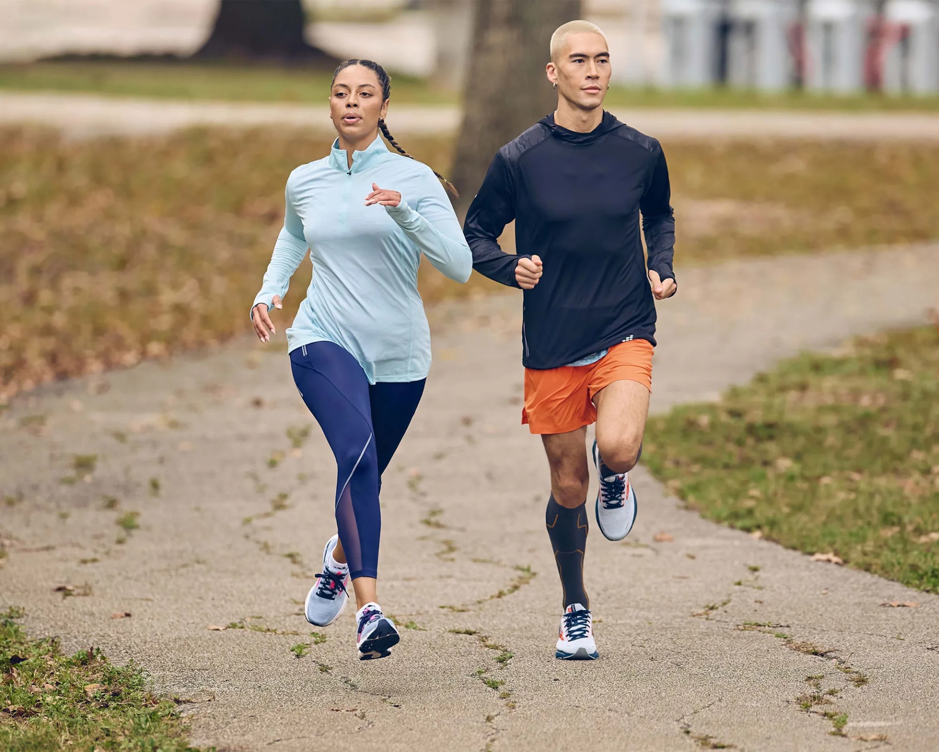 a woman and man jogging down a paved winding road
