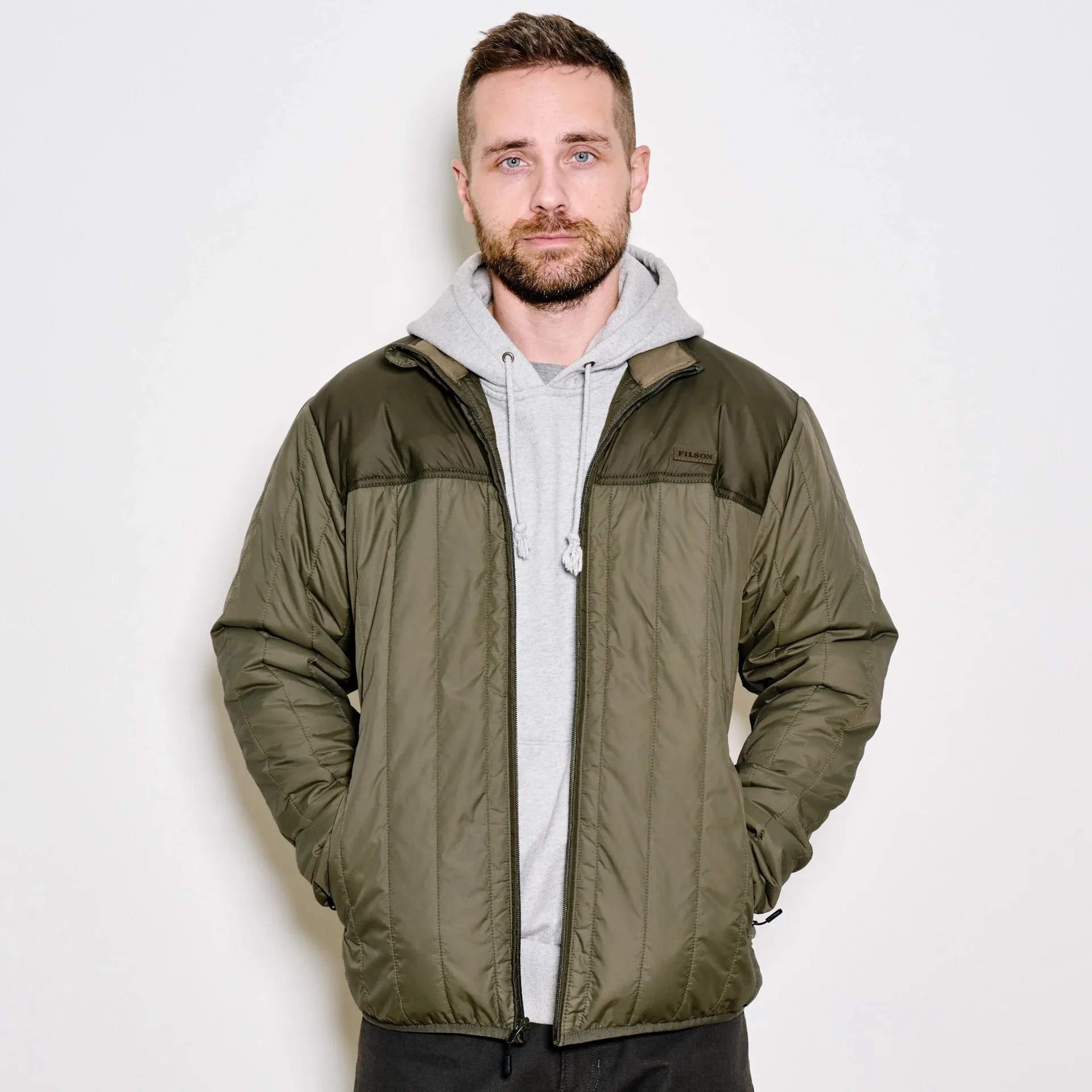 Filson ultralight jacket in moss being worn by male wearing hoody unzipped
