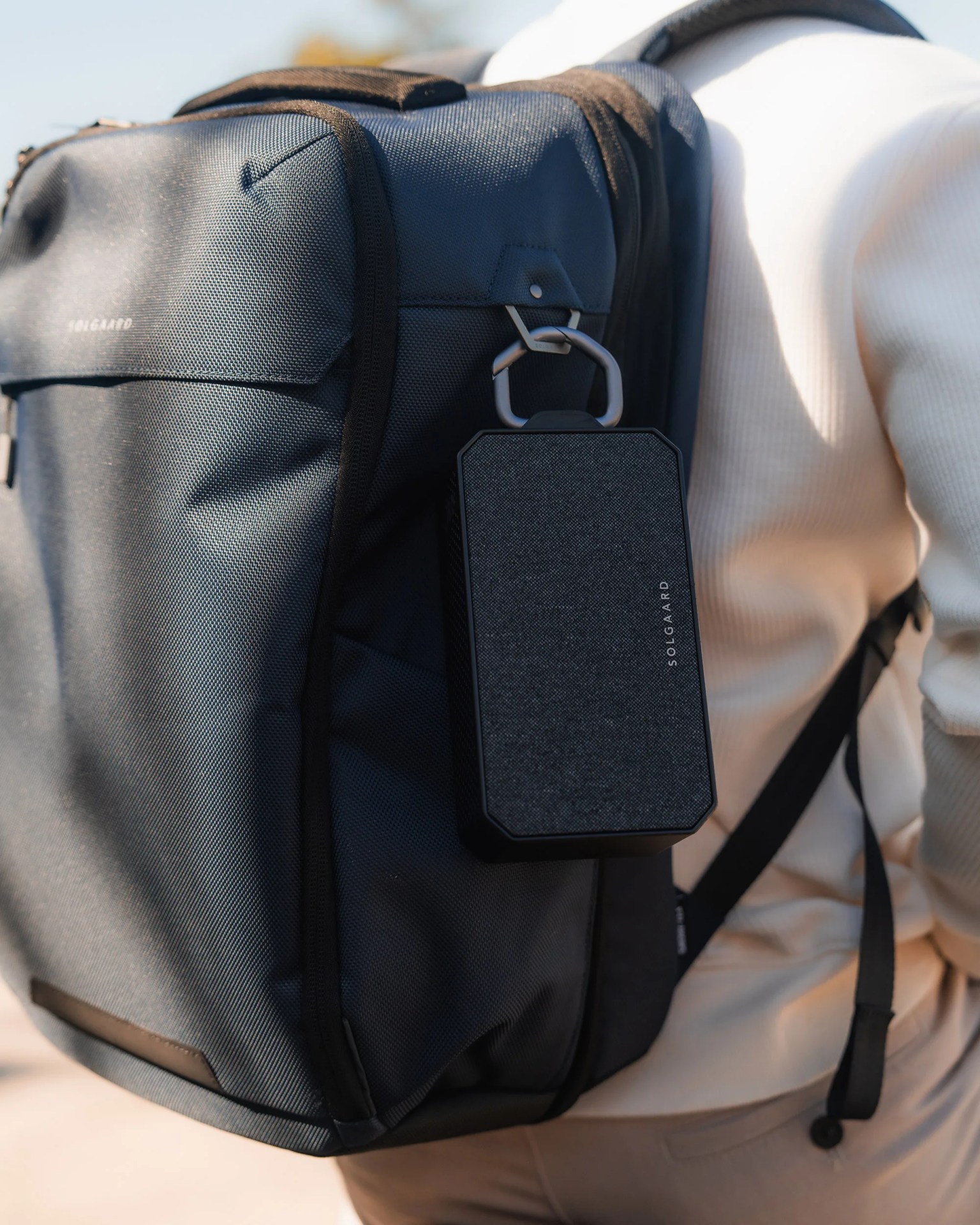 person hanging Solgaard Solar Boombox on backpack