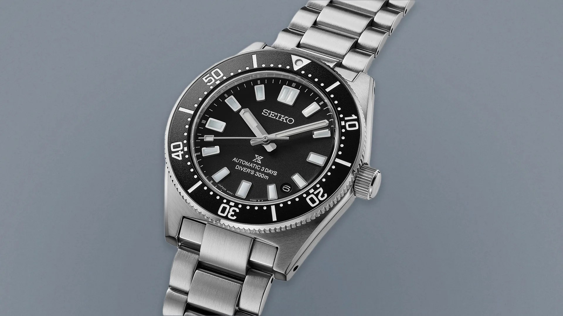 a silver and black seiko watch on a gray background
