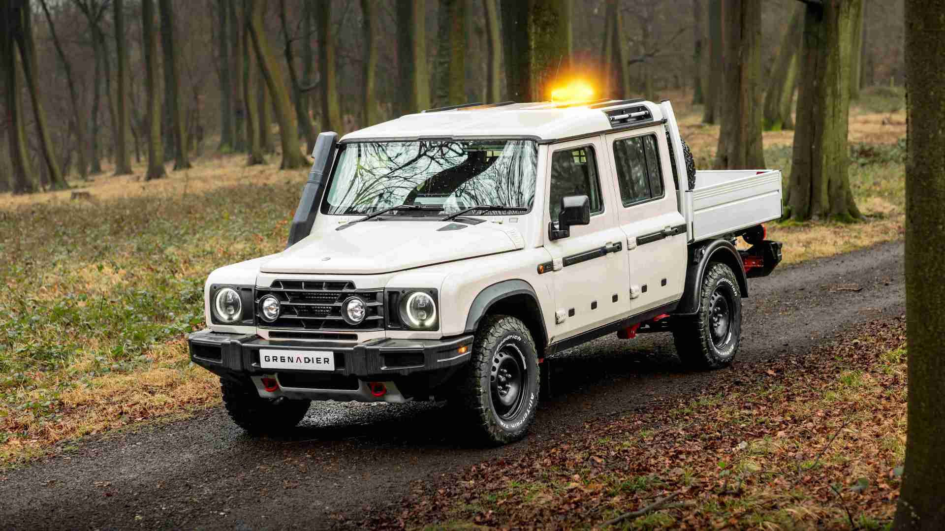 Ineos Grenadier Quartermaster chassis cab pickup driving through woods