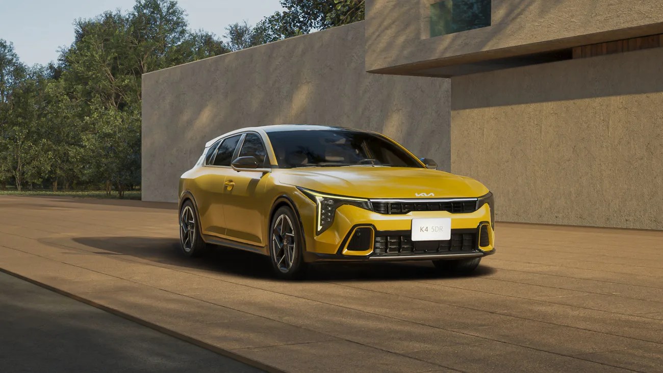 yellow kia hatchback in front of a brutalist building
