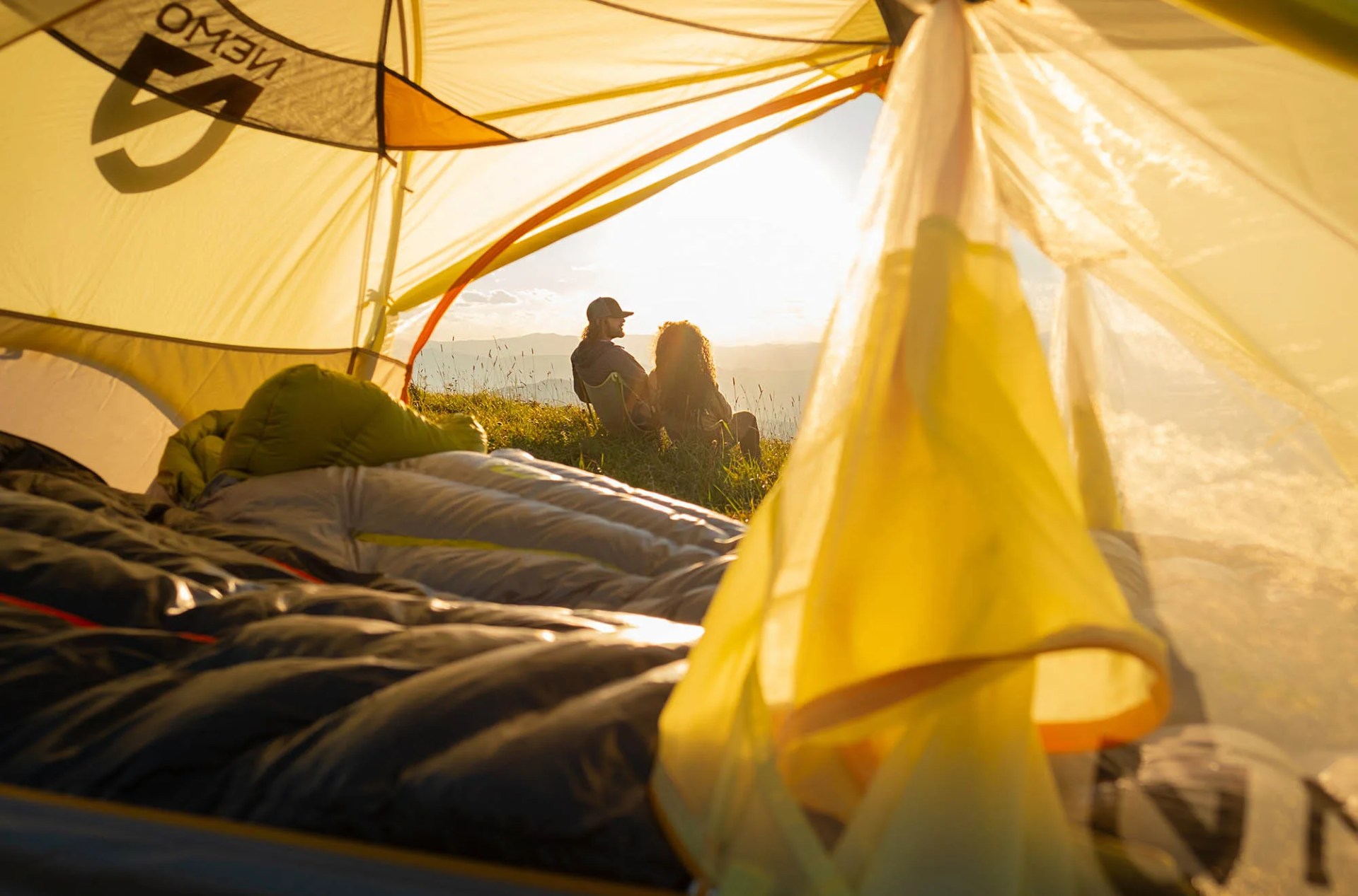 looking out from a Nemo tent flap at a man and woman