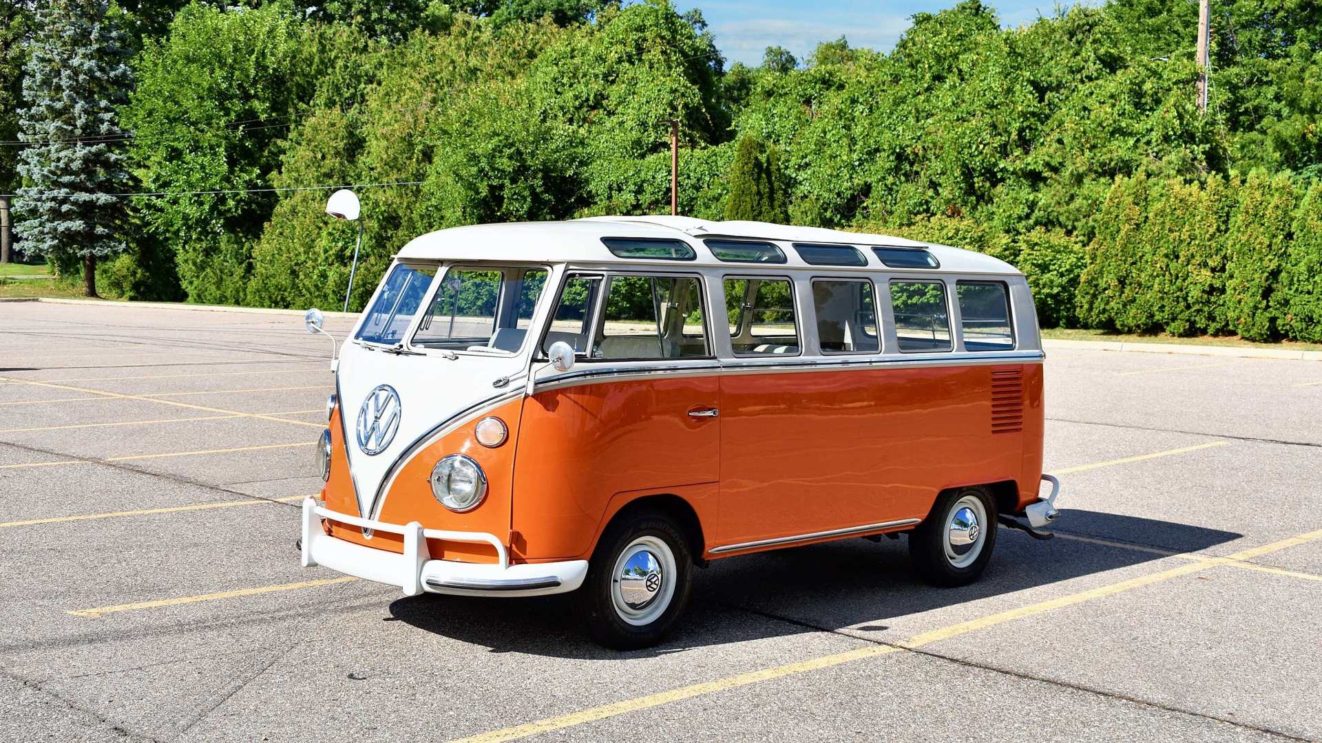 Old VW bus in a parking lot with trees in the background