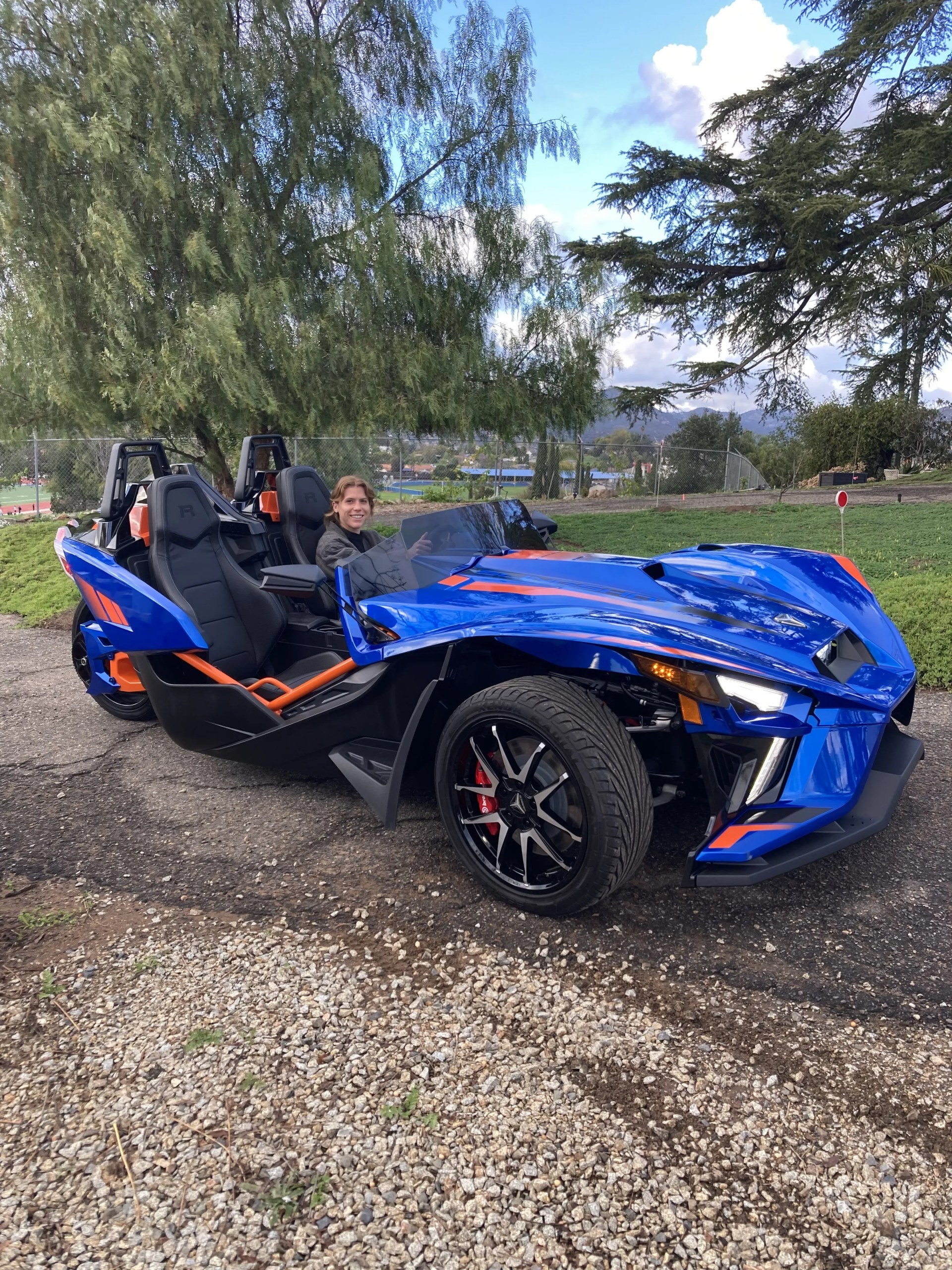 woman sitting in a polaris slingshot r on a country road