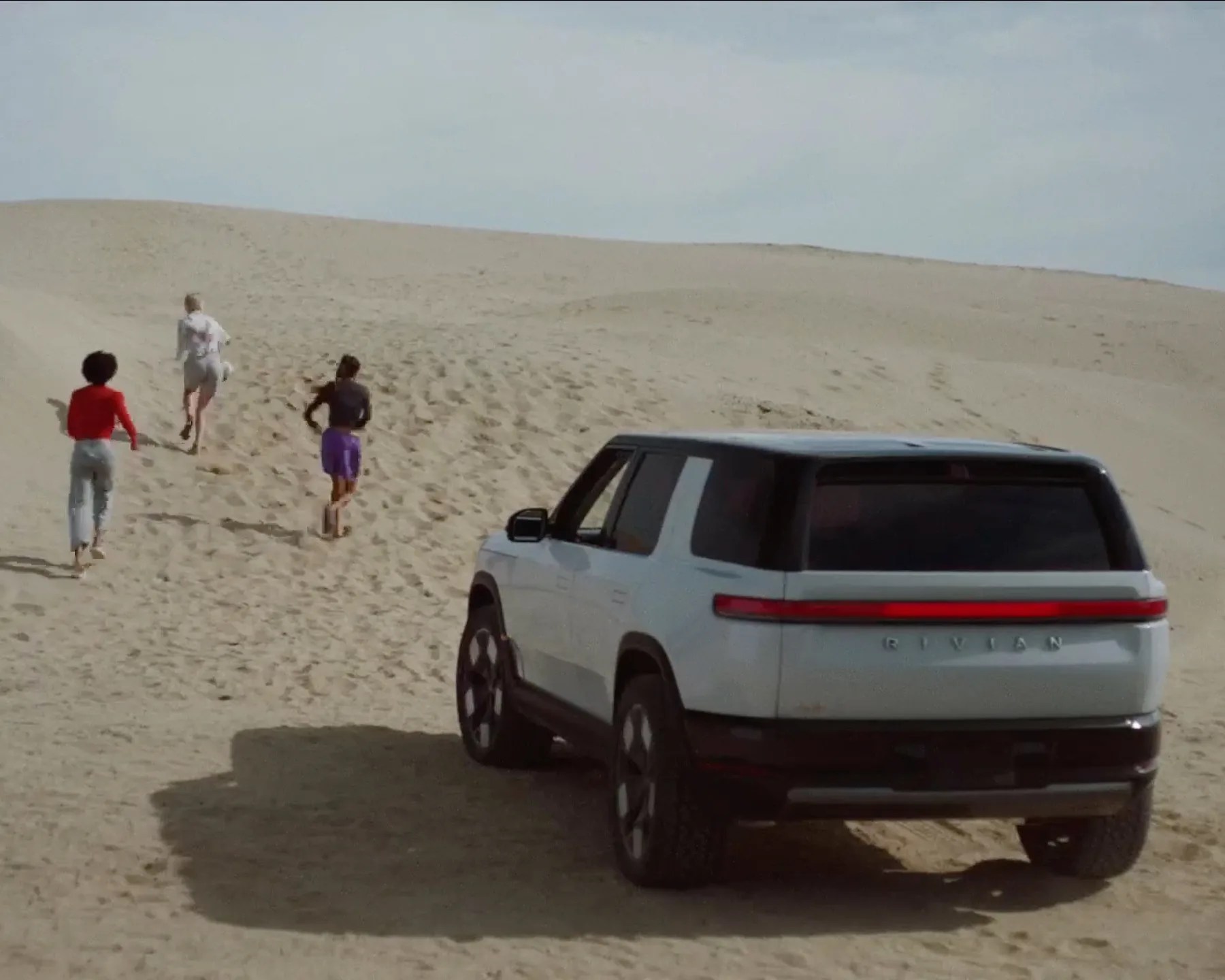 rivian r2 seen from the rear on a beach