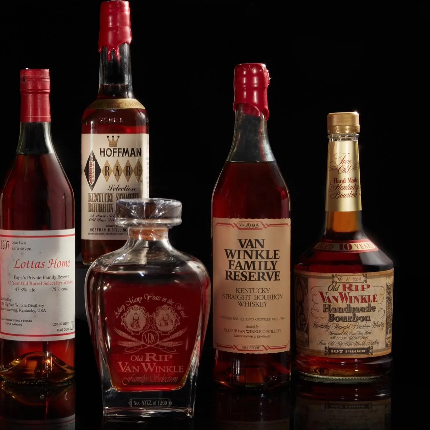 several bottles of antique pappy van winkle whiskeys against a black background
