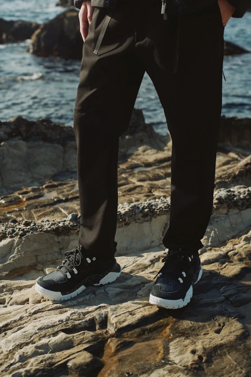 person wearing timberland x white mountaineering shoes on a rock