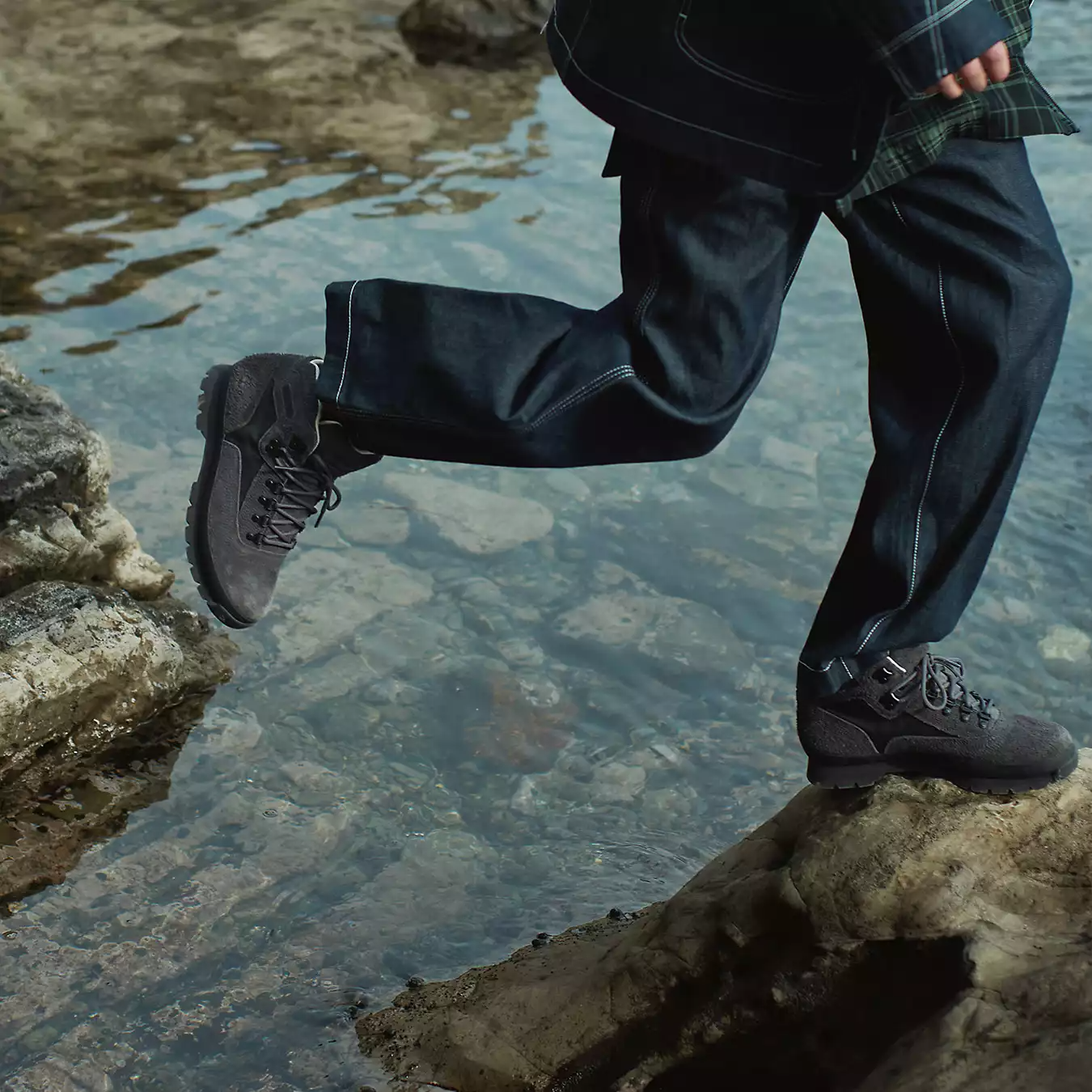 person jumping over water wearing timberland x white mountaineering boots