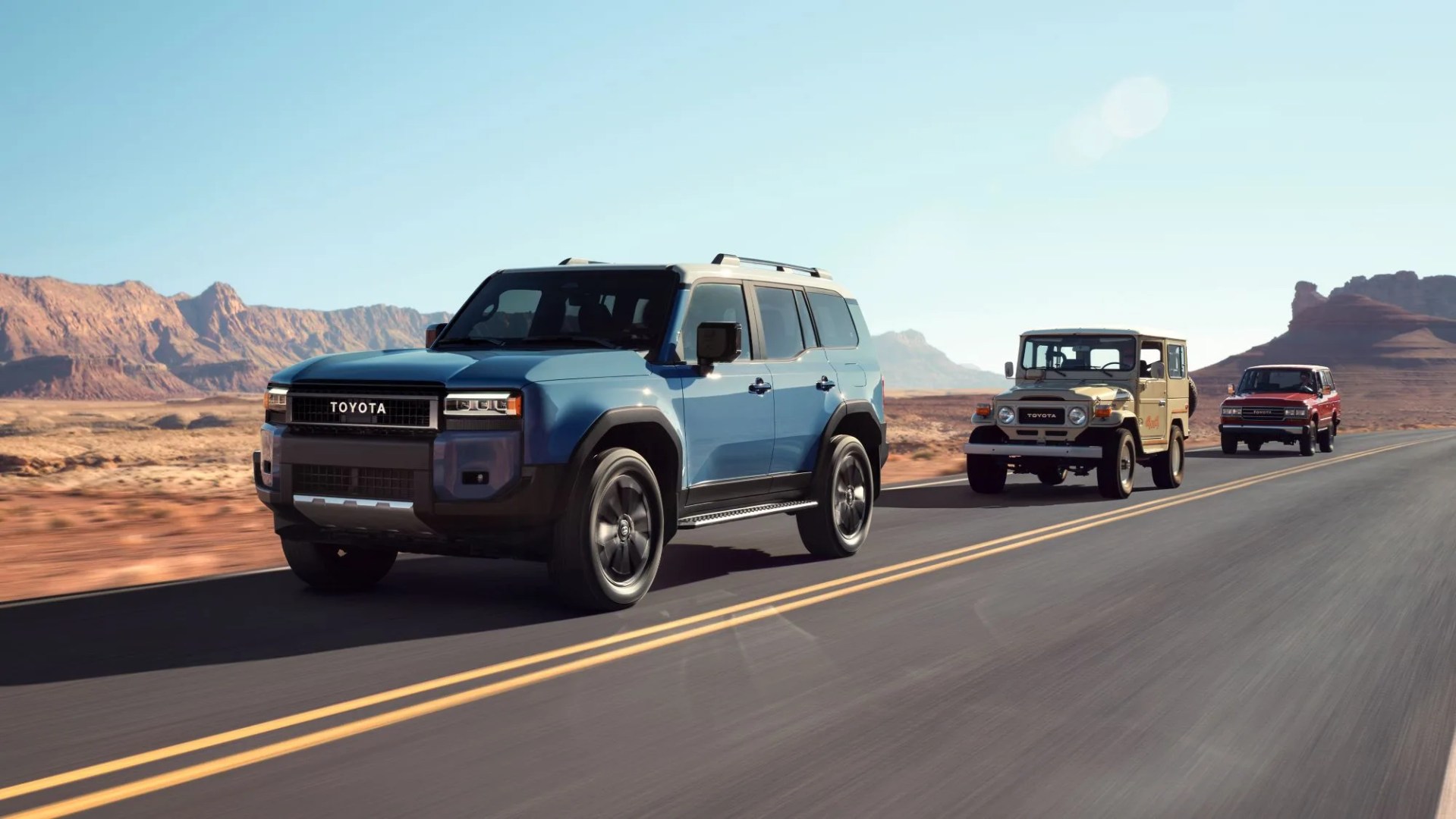 A new 2024 Toyota Land Cruiser driving down a dessert highway followed by two vintage Toyota Land Cruisers from the past.