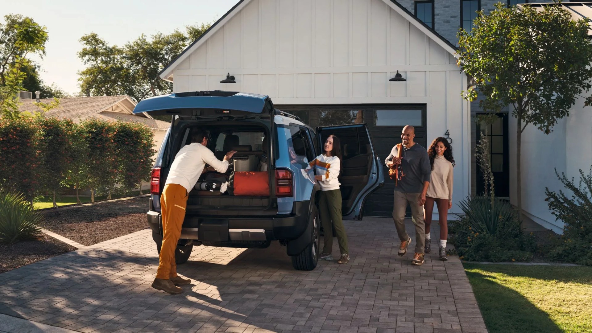 2024 Toyota Landcruiser in residential driveway being packed up by family for a weekend trip.