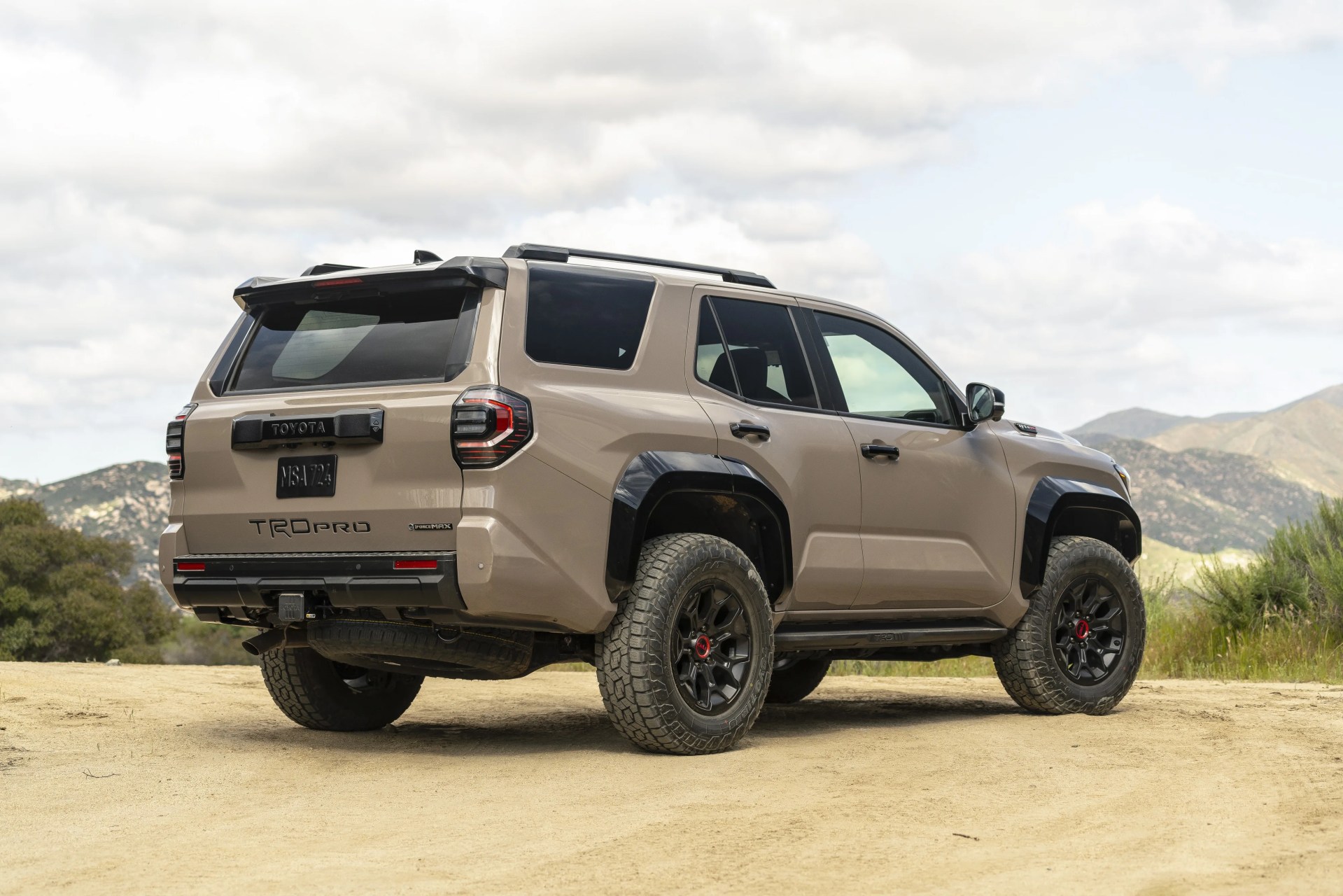 2025 Toyota 4Runner in Mudbath color shown from rear on dirt road.