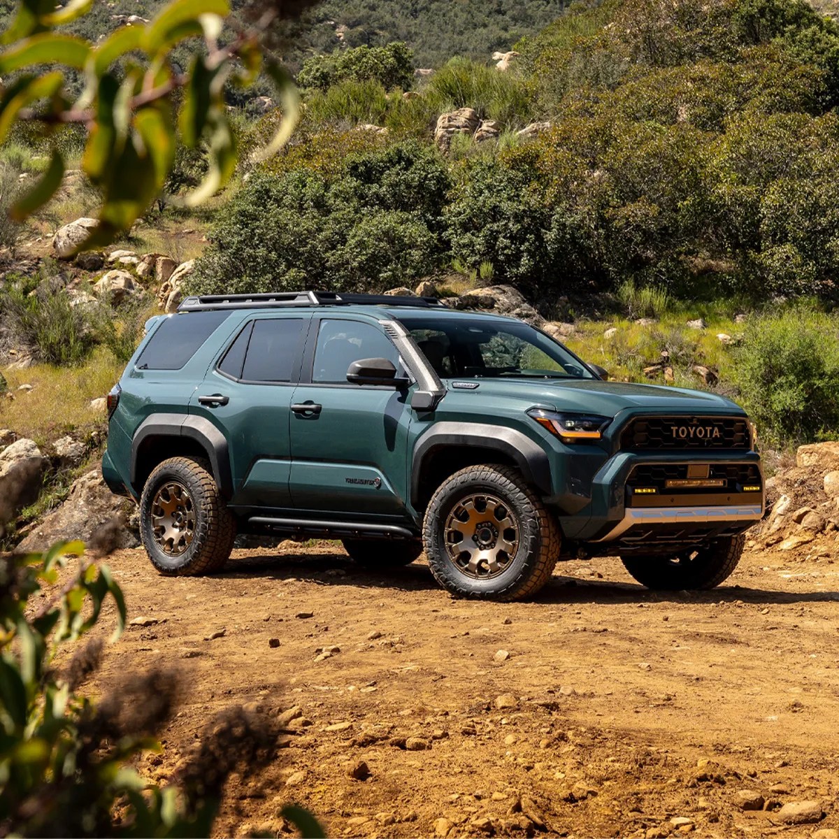 2025 Toyota 4Runner Trailhunter edition in Everest color parked in dirt road with trees in background