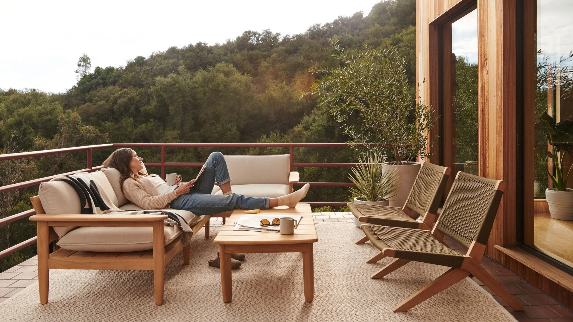 Burrow dunes sofa collection on back porch with woman sitting feed on coffee table looking out at trees