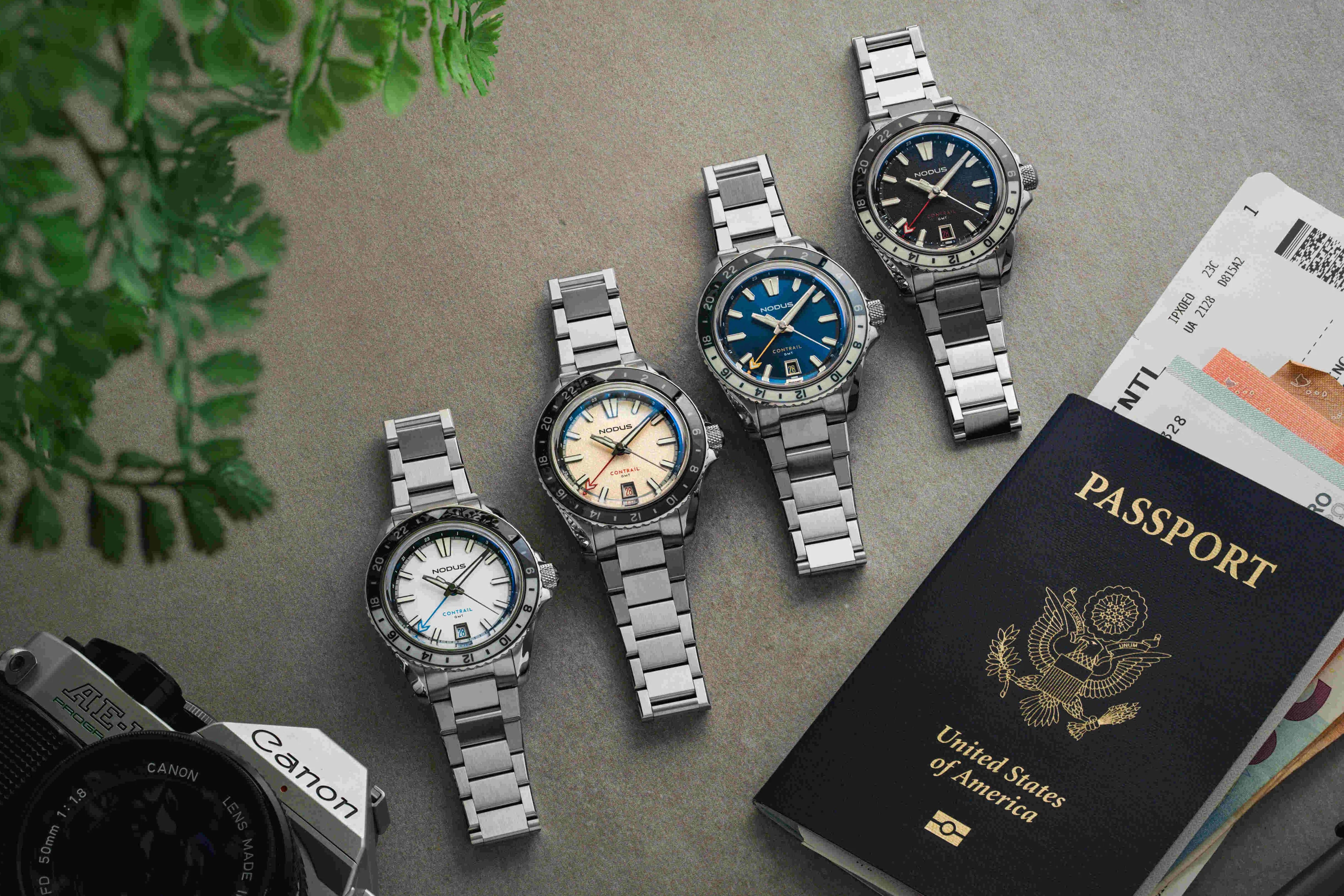 four nodus watches next to a passport and camera